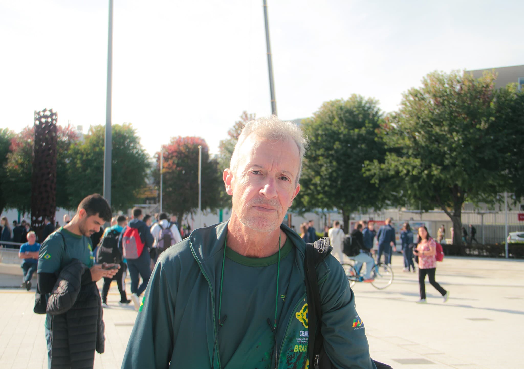 Retrato de um integrante da delegação brasileira com uniforme da CBKKO em uma praça.